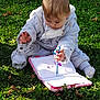toddler, child, grass, notebook, pen, scribbling, outdoor, greenery, clothing, cute, baby, sitting, sunlight, nature, playful, writing, concentration, casual, young, park