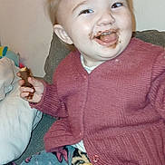 Inaya a rejoint le concours — aidez-le/la à gagner de superbes lots ! blanket, child, chocolate, comfort, couch, cozy, cute, face, food, hand, happy, indoor, pants, person, playful, sitting, smile, snack, sweater, toddler