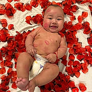 Ethan is registered to the contest to win money with this photo: baby, child, infant, smiling, portrait, lying_down, rose_petals, red_flowers, valentines_day, heart_decoration, diaper, bare_chested, outdoorless, close_up, happy, face, arms, legs, blanket, photography