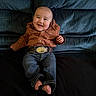 baby, child, smiling, jeans, shirt, belt, barefoot, couch, blue_couch, indoor, portrait, happy, young_child, seated, clothing, footwear, face, person, casual, cute