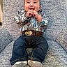 baby, child, smiling, jeans, shirt, belt, cowboy_belt, socks, chair, seated, happy, portrait, indoor, person, cute, infant, patterned_clothing, hands, face, furniture