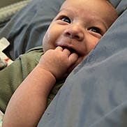 Colter is registered to the contest to win money with this photo: baby, infant, smiling, hand, face, blanket, cozy, cute, child, lying_down, happy, skin, fingers, bedroom, soft, comfort, young, person, expression, indoors