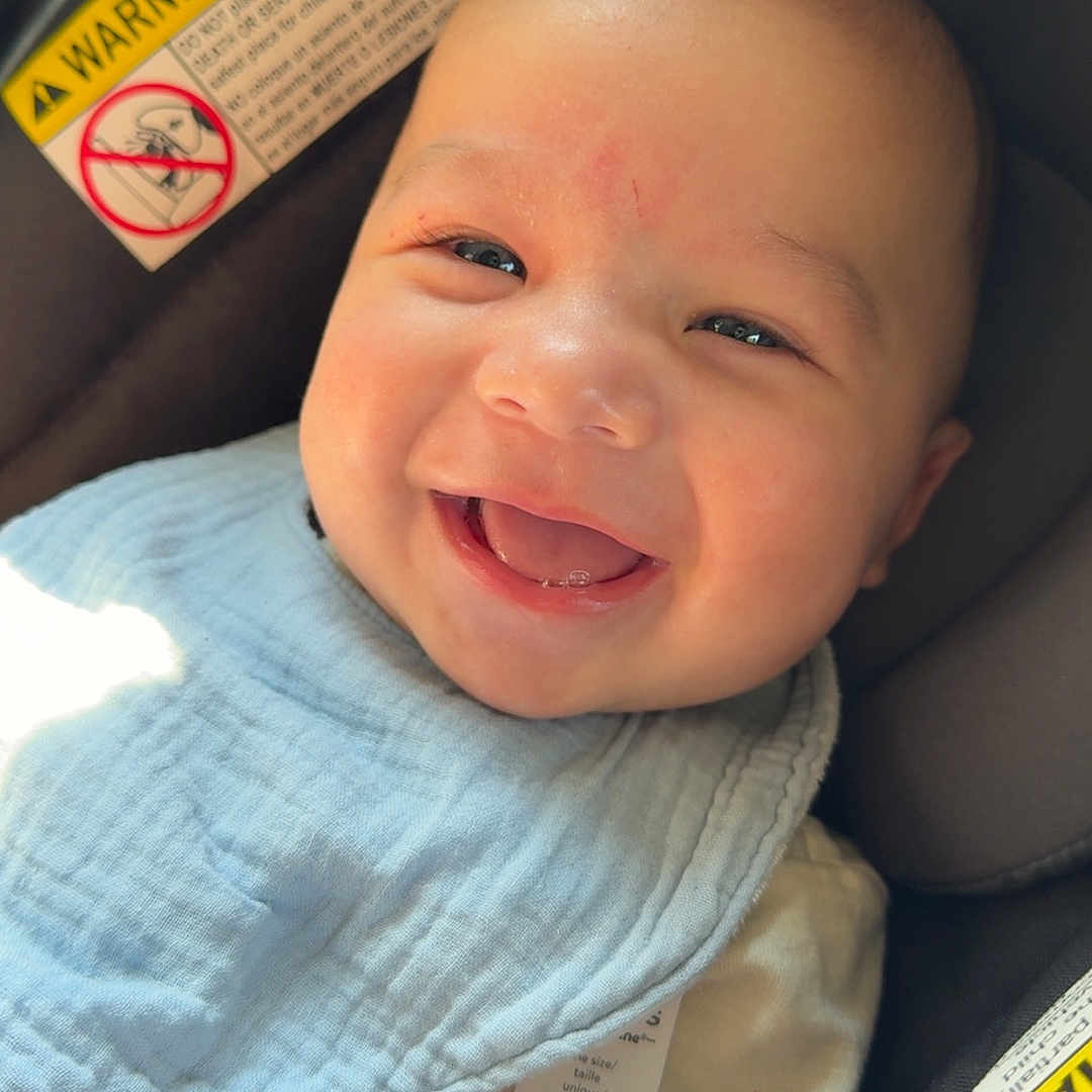 Colter joined the competition — help win amazing prizes! baby, smiling, car_seat, bib, infant, child, cute, happy, portrait, sunlight, clothing, seat, warning_label, skin, face, head, small_person, childhood, comfort, indoor