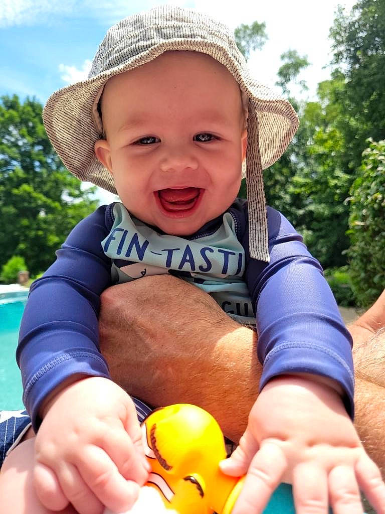 August is registered to the contest to win money with this photo: baby_toddler_clothing, child, cloud, finger, fun, grass, hand, happy, hat, joy, leisure, people_in_nature, person, photograph, recreation, skin, sky, smile, sun_hat, thumb