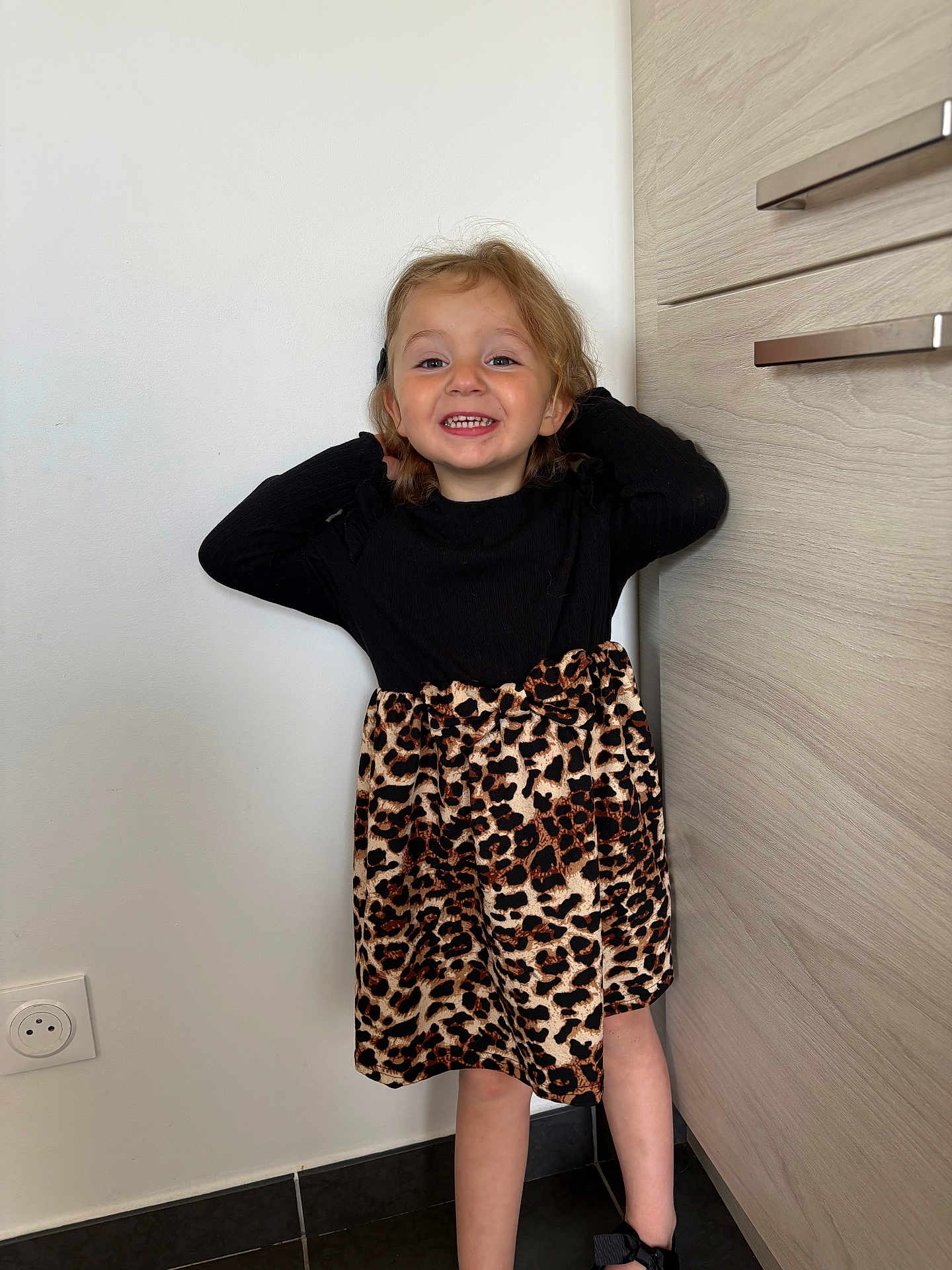 Lilou a rejoint le concours — aidez-le/la à gagner de superbes lots ! child, girl, smiling, leopard_print, skirt, black_top, standing, indoor, corner, floor_tile, wall, cabinet, happy, pose, young, person, feet, hair, fashion, cute