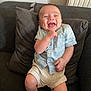 baby, smile, happy, child, couch, pillow, clothing, shorts, shirt, indoor, furniture, person, infant, sitting, joy, face, skin, leg, hand, radiator