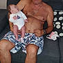 Lyna participe au concours pour gagner de l'argent avec cette photo : apple, baby, bottle, bracelet, carpet, couch, fruit_basket, furniture, holding, home, indoor, infant, looking, man, necklace, person, pillow, shirtless, shorts, sitting