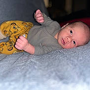 Jude participe au concours pour gagner de l'argent avec cette photo : baby, blanket, cartoon_lion, child, closeup, clothing, curious, cute, face, hands, indoors, infant, lying_down, person, portrait, resting, socks, soft_texture, yellow_pants, young