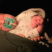 Jude a rejoint le concours — aidez-le/la à gagner de superbes lots ! baby, pacifier, sleeping, blanket, infant, cozy, hand, face, soft_light, dark_background, clothing, newborn, peaceful, portrait, cute, indoors, closeup, resting, child, comfort