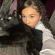 Nieko is registered to the contest to win money with this photo: girl, cat, black_cat, selfie, curly_hair, indoor, wide_eyes, holding, bed, blanket, young_person, portrait, pet, animal, feline, face, expression, cozy, casual, white_shirt