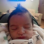 Aiden joined the competition — help win amazing prizes! baby, sleeping, mohawk, blanket, dinosaur_print, clothing, face, infant, indoor, cozy, living_room, couch, television, soft_lighting, peaceful, child, person, portrait, cute, resting