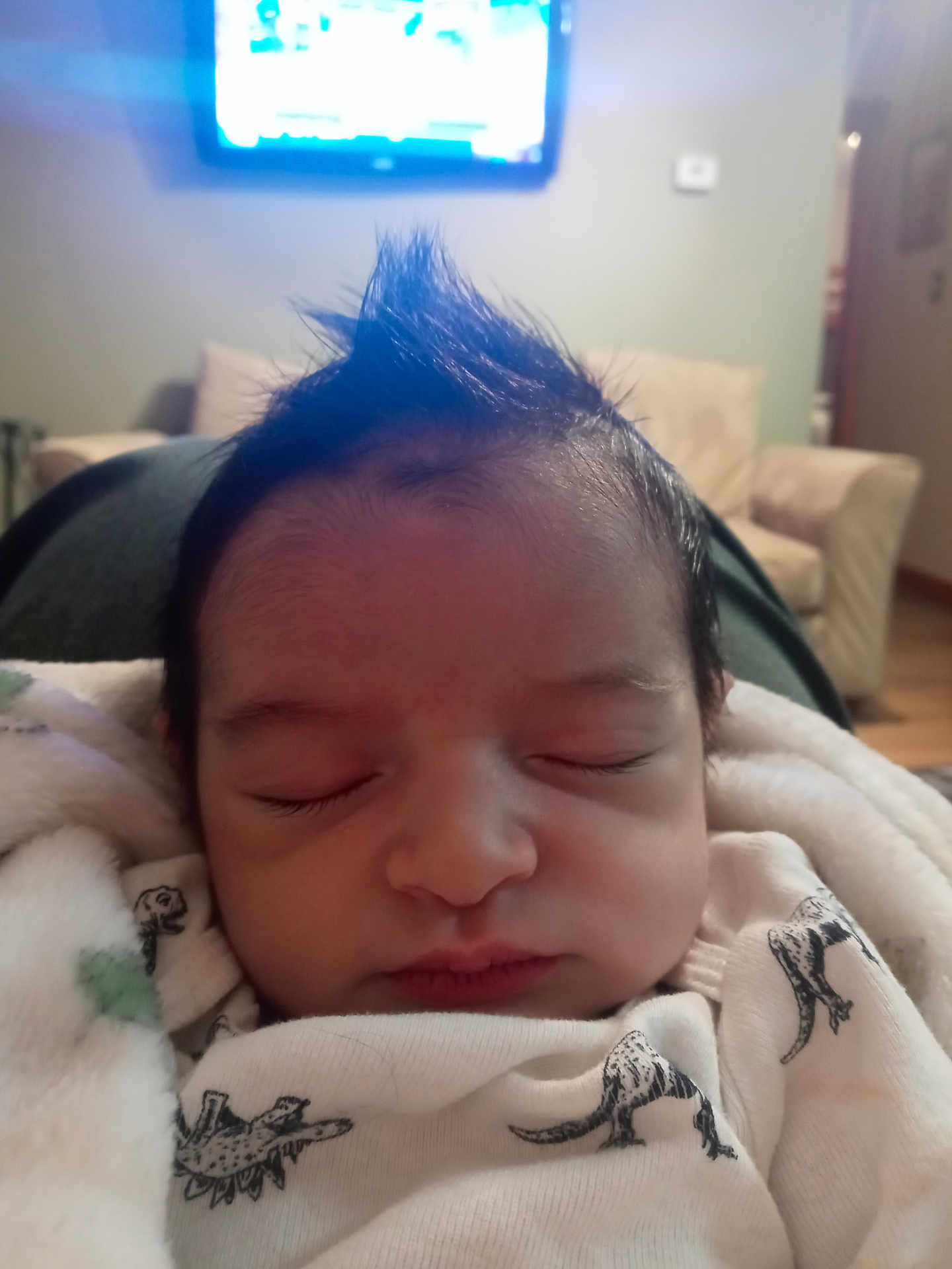 Aiden joined the competition — help win amazing prizes! baby, sleeping, mohawk, blanket, dinosaur_print, clothing, face, infant, indoor, cozy, living_room, couch, television, soft_lighting, peaceful, child, person, portrait, cute, resting
