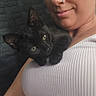 woman, person, cat, kitten, black_cat, pet, selfie, portrait, cuddling, sitting, indoors, close_up, face, eyes, nose_ring, white_top, textured_background, feline, companion, cozy