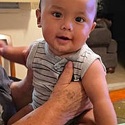 Isaac joined the competition — help win amazing prizes! baby, child, person, indoor, holding, striped_clothing, smiling, cute, arm, hand, furniture, living_room, portrait, skin, head, face, eyes, infant, seated, happy