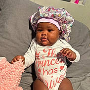 Kulture is registered to the contest to win money with this photo: baby, child, infant, onesie, bonnet, unicorn, blanket, couch, indoor, cute, portrait, sitting, pink, white, fabric, clothing, hand, face, headwear, soft