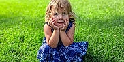 Brooklyn joined the competition — help win amazing prizes! blue_dress, casual, child, childhood, curly_hair, cute, daylight, face, girl, grass, greenery, hands, nature, outdoor, park, playful, portrait, sitting, summer, young