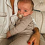 adult_hand, baby, blinds, child, close_up, comfort, couch, face, holding, home, indoor, necklace, pacifier, pajamas, person, relaxation, seated, skin, striped_pajamas, window