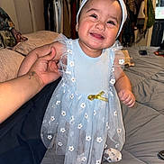 Gianna joined the competition — help win amazing prizes! baby, child, smiling, dress, headband, bow, hand, bedroom, clothes, hanger, bed, blanket, person, infant, cute, happy, indoor, toddler, fabric, portrait