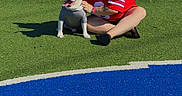 Galen Erso joined the competition — help win amazing prizes! person, dog, artificial_turf, sports_jersey, white_dog, gray_shirt, outdoor, sunny, grass, blue_stripe, red_stripe, pavement, smiling, sitting, pet, tongue_out, casual, happy, playful, daylight