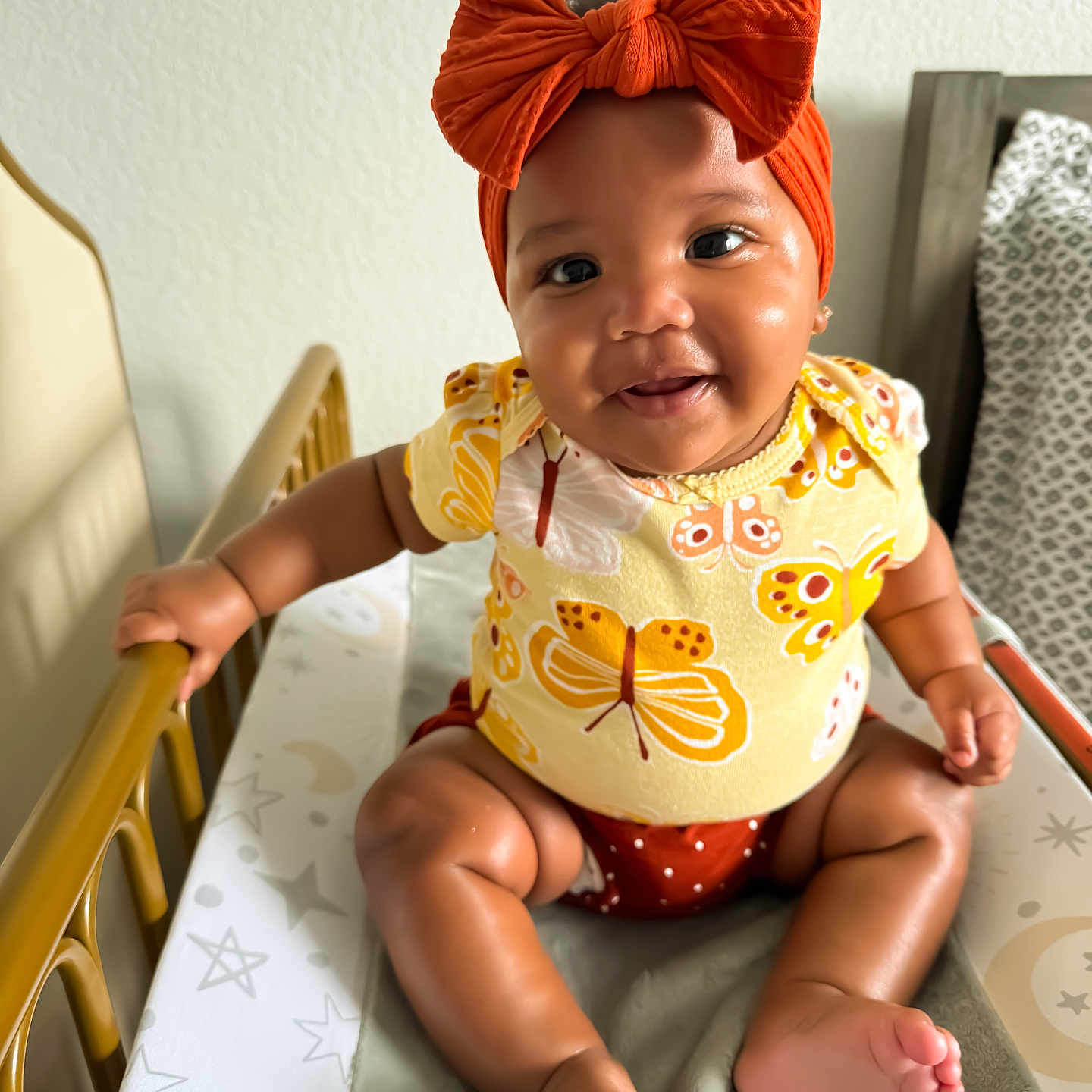 Savannah is registered to the contest to win money with this photo: baby, bed, bodypart, clothing, couch, crib, dress, face, finger, furniture, hand, handrail, happy, head, infantbed, person, photography, portrait, sitting, smile