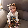 baby, casual, child, colorful_clothing, couch, cozy, cute, expression, floral_pattern, furniture, girl, headband, home, indoor, person, pink_socks, portrait, sitting, white_shirt, young_child