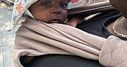 Emori joined the competition — help win amazing prizes! adult, baby, baby_carrier, baby_wrap, black_clothing, chain_necklace, closeup, daylight, face, hat, headwear, human, infant, outdoor, person, shoulder, sidewalk, skin, street, sun_hat