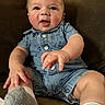 baby, child, infant, romper, blue_clothing, anchor_pattern, couch, brown_furniture, sock, footwear, hand, face, smile, happy, indoors, portrait, seated, cute, young, person