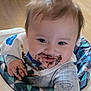 Mavrik is registered to the contest to win money with this photo: baby, child, chocolate, messy, high_chair, smile, face, hands, clothing, bib, patterned, indoor, happy, cute, infant, food, snack_time, playful, expression, fun