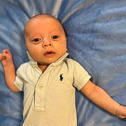Brantley joined the competition — help win amazing prizes! baby, infant, polo_shirt, blue_blanket, lying_down, curious, wide_eyes, cute, soft_texture, indoor, child, portrait, human, young, one_person, casual_clothing, small_logo, skin, head, arm