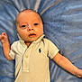 baby, infant, polo_shirt, blue_blanket, lying_down, curious, wide_eyes, cute, soft_texture, indoor, child, portrait, human, young, one_person, casual_clothing, small_logo, skin, head, arm