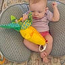 April is registered to the contest to win money with this photo: baby, infant, plush_toy, cushion, playpen, animal_print, child, indoors, purple_shirt, pink_shorts, barefoot, toy, seated, cute, soft_toy, fabric, play_area, young_child, person, baby_girl