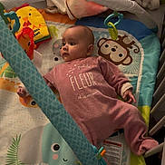 Kaëlya a rejoint le concours — aidez-le/la à gagner de superbes lots ! baby, crib, play_mat, toy, blanket, onesie, infant, face, child, colorful, soft_toy, furniture, cute, indoor, sleepwear, person, animal_print, smile, resting, curious