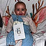 baby, infant, smile, face, eyes, blanket, name_text, antlers, denim_overall, pink, milestone_card, six_months, card, sitting, feet, portrait, cozy, cute, photography, chubby_cheeks
