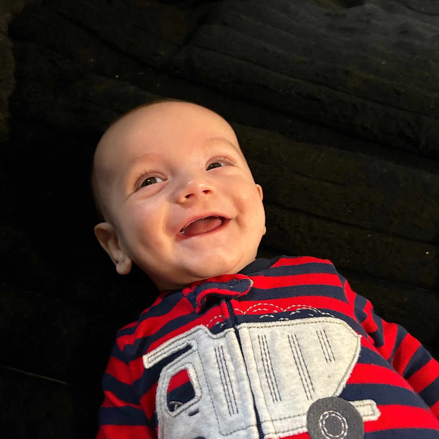 Jackson joined the competition — help win amazing prizes! baby, smiling, infant, child, striped_clothing, red_clothing, navy_clothing, truck_applique, happy, lying_down, face, cute, joyful, portrait, apparel, young_child, indoors, fabric, texture, human