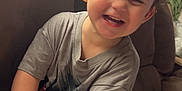 Dominic is registered to the contest to win money with this photo: toddler, child, smiling, laughing, indoor, couch, toy, cat, pet, furniture, cozy, happy, person, casual_clothing, short_sleeves, brown_hair, relaxed, cute, home, living_room