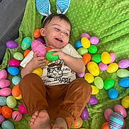Dominic is registered to the contest to win money with this photo: toddler, child, bunny_ears, easter_eggs, green_blanket, plastic_eggs, happy, smiling, playful, indoor, clothing, feet, hands, headwear, toy, colorful, celebration, holiday, person, cute