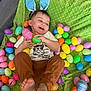 toddler, child, bunny_ears, easter_eggs, green_blanket, plastic_eggs, happy, smiling, playful, indoor, clothing, feet, hands, headwear, toy, colorful, celebration, holiday, person, cute