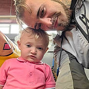 Arlo-Alexander joined the competition — help win amazing prizes! background, beard, casual_clothing, chair, child, closeup, curly_hair, face, family, indoor, man, natural_light, person, pink_shirt, portrait, selfie, smile, stacked_chairs, toddler, window