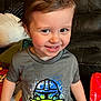 child, toddler, smiling, indoors, tshirt, baby_yoda, mandalorian, couch, cushion, toy, happy, face, short_sleeves, camouflage_pants, hair, person, clothing, living_room, cute, playful