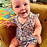 armchair, baby, blue_eyes, child, close_up, couch, daylight, floral_pattern, happy, home, indoor, infant, living_room, play_mat, playroom, portrait, romper, sitting, smiling, toy