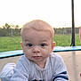 baby, child, crawling, trampoline, outdoor, grass, field, sky, young_child, infant, curious, casual_clothing, long_sleeve, daylight, nature, playtime, portrait, face, hand, person