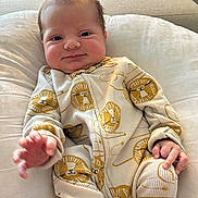 Elias joined the competition — help win amazing prizes! baby, infant, onesie, lion_pattern, pillow, couch, indoor, hand, face, expression, clothing, soft_light, comfort, child, portrait, cute, smiling, reaching_hand, fabric, home