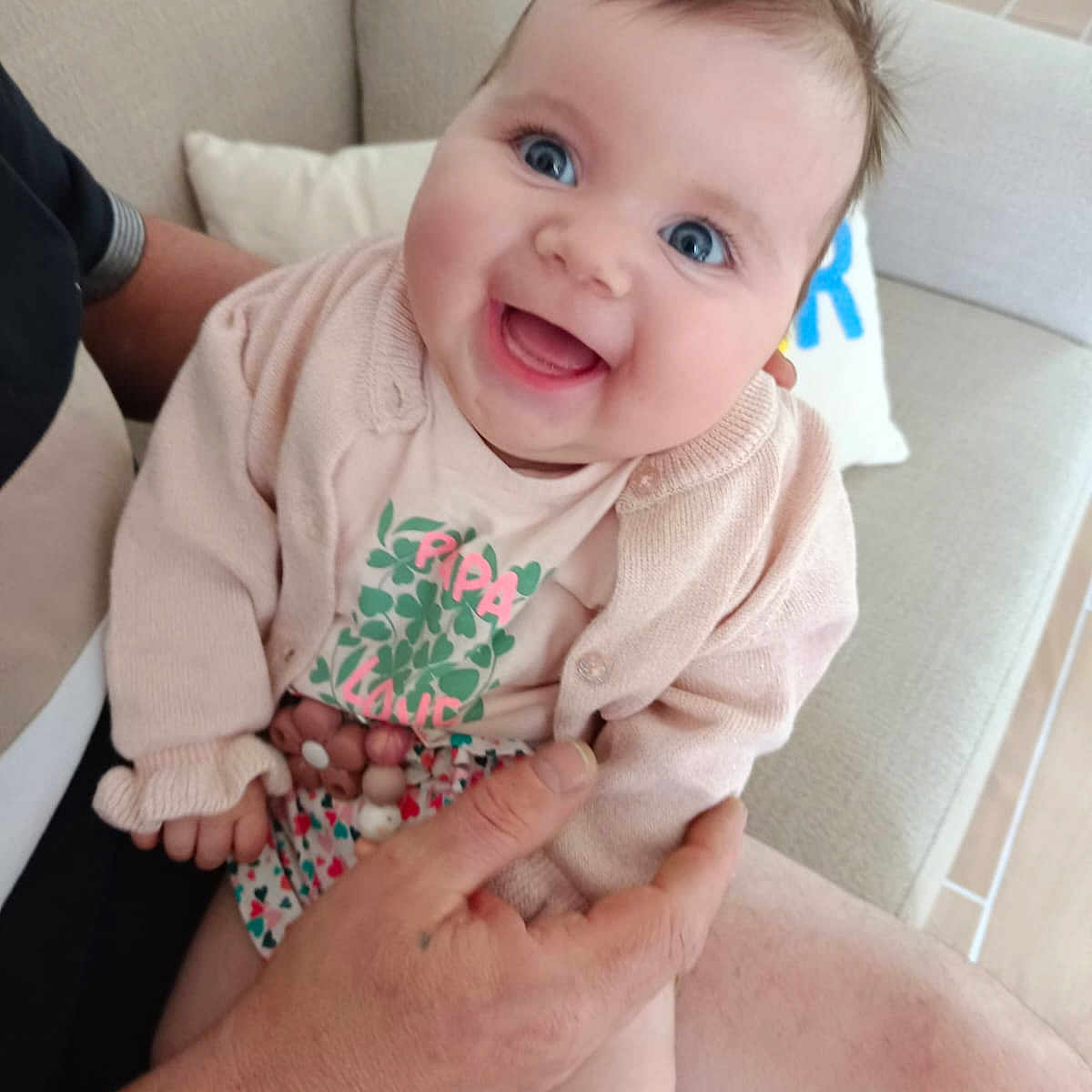 Rose a rejoint le concours — aidez-le/la à gagner de superbes lots ! adult, baby, beige, blue_eyes, child, clothing, couch, cute, furniture, hand, happy, human, indoor, infant, joy, person, pink_cardigan, portrait, sitting, smiling