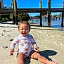 toddler, child, beach, sand, sunny, water, dock, pier, swimsuit, smiling, outdoor, daylight, happy, nature, vacation, summer, person, curly_hair, playful, shore