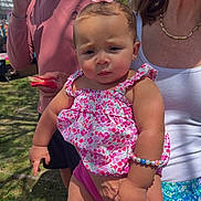 Paisley joined the competition — help win amazing prizes! baby, child, person, woman, adult, outdoor, daylight, grass, pink_clothing, floral_pattern, bracelet, bow, holding, summer_clothing, snack, casual, portrait, expression, family, nature