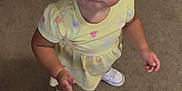 Paisley is registered to the contest to win money with this photo: toddler, child, curly_hair, yellow_dress, white_sneakers, carpet, crib, indoor, looking_up, standing, earrings, cute, curious, person, young_child, baby, small_hands, floor, home, innocent
