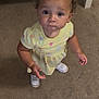 toddler, child, curly_hair, yellow_dress, white_sneakers, carpet, crib, indoor, looking_up, standing, earrings, cute, curious, person, young_child, baby, small_hands, floor, home, innocent