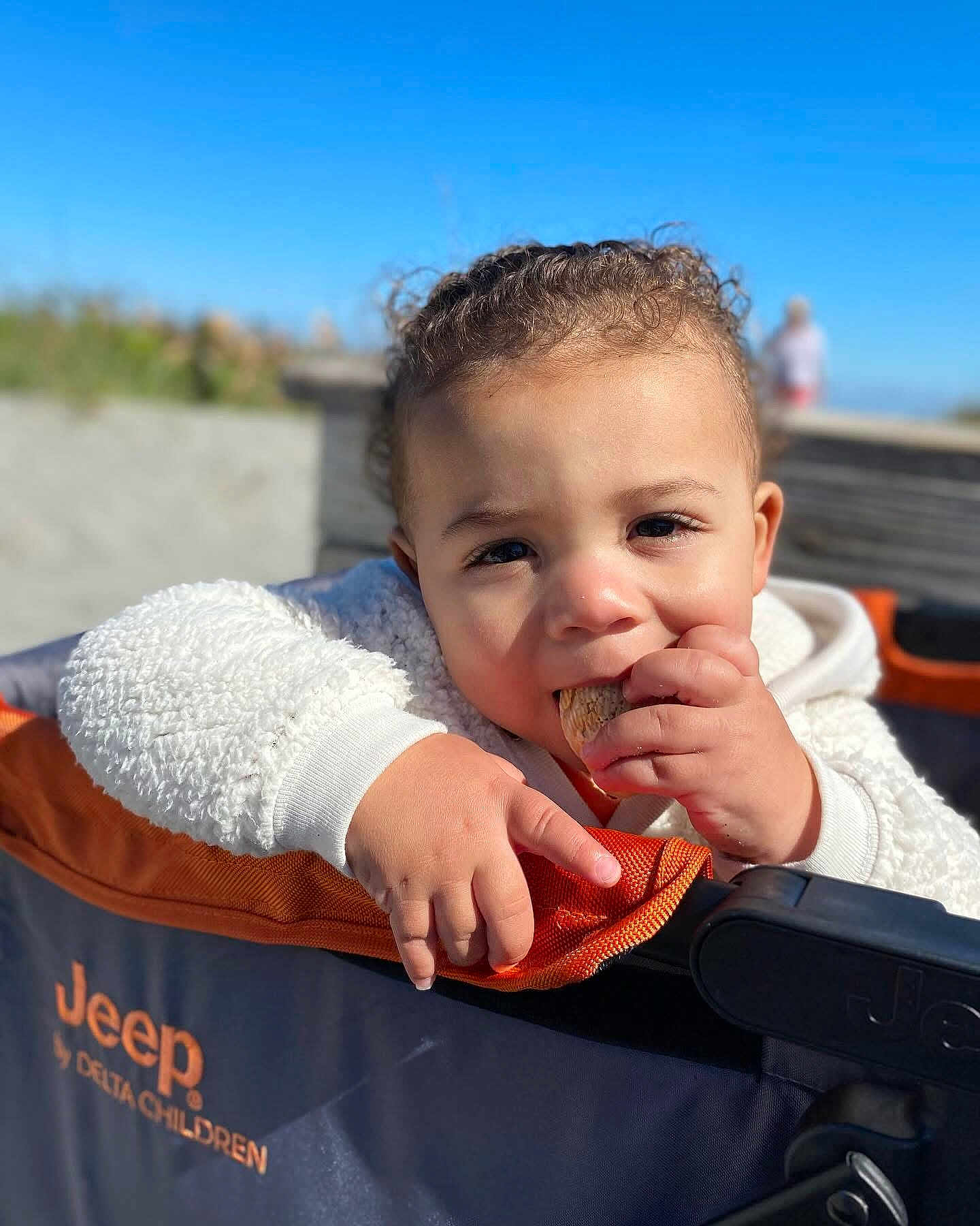 Preston joined the competition — help win amazing prizes! toddler, child, curly_hair, snack, stroller, jeep, outdoor, blue_sky, sunlight, face, hand, clothing, orange, navy, fabric, portrait, baby, cute, daylight, blurred_background