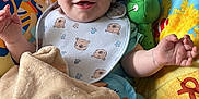Robin is registered to the contest to win money with this photo: baby, smiling, bib, blanket, play_mat, toy, turtle, sea_creatures, colorful, infant, cute, happy, child, indoor, soft_toy, clothing, sock, face, person, portrait