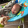Robin is registered to the contest to win money with this photo: baby, blanket, smiling, baby_rocker, toy, floor, indoor, child, happy, clothing, face, head, person, seat, colorful, comfort, infant, wooden_floor, playful, cozy